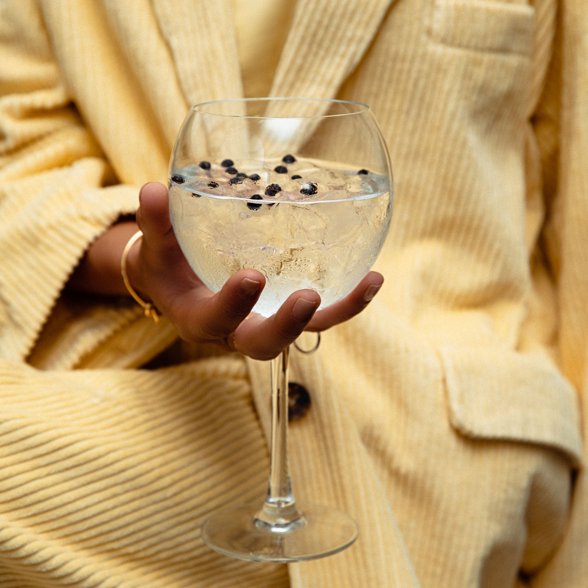 The perfect service, a glass with ice cubes, Panda Gin and Tonic premium. On a yellow background